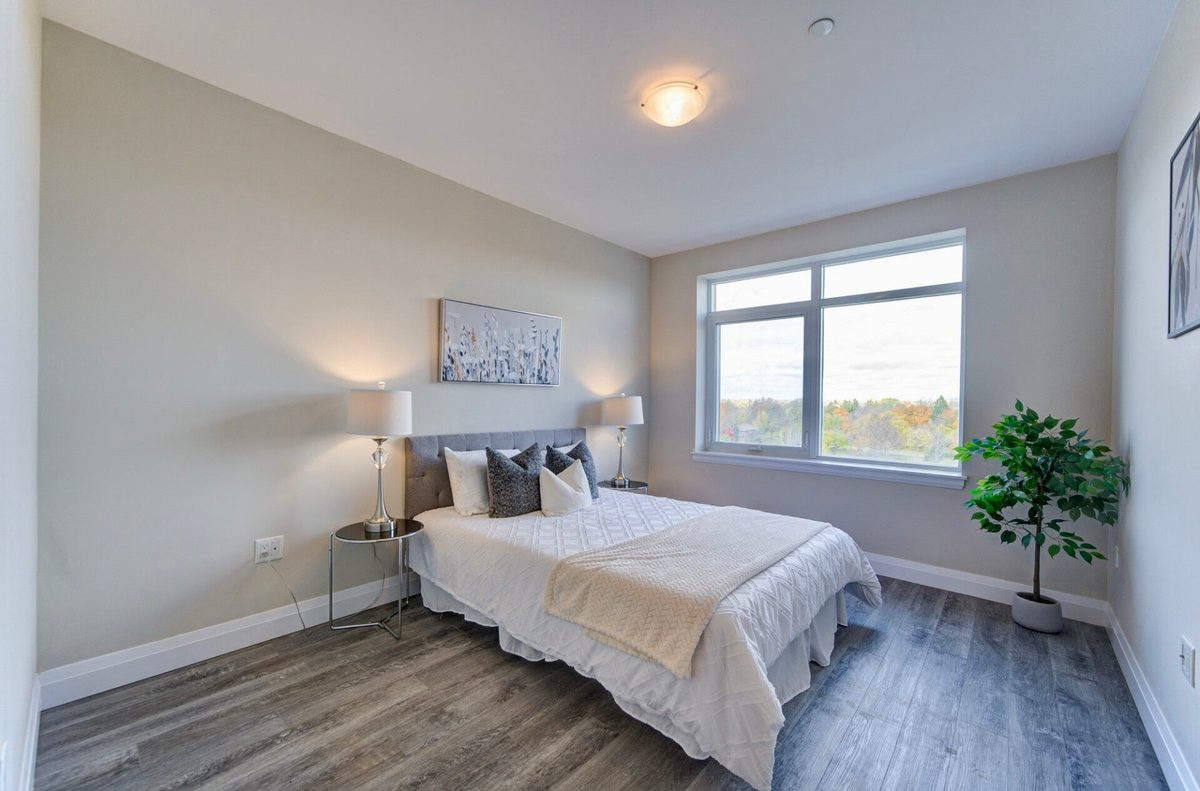 A bright bedroom with a large window looking out over autumn trees